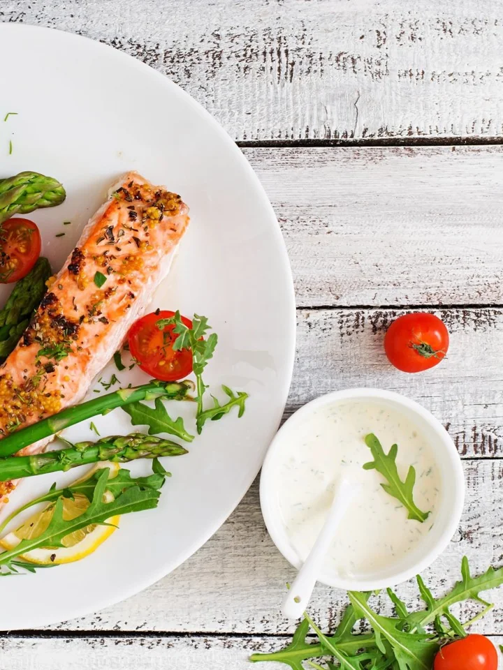 A plated salmon fillet with asparagus, rocket and a herb sauce